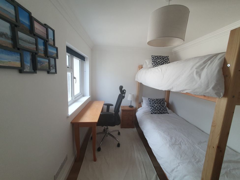 A bedroom with a bunk bed and desk at Sea View Beach Apartment Thurlestone