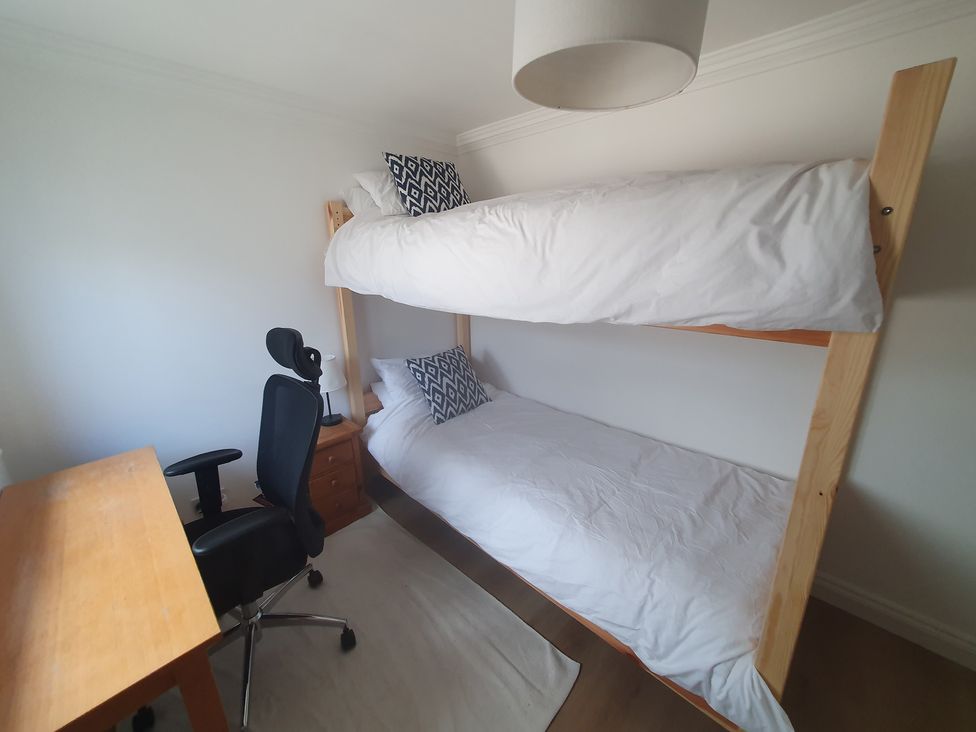 A bedroom with a bunk bed and a desk at Sea View Beach Apartment in Thurlestone