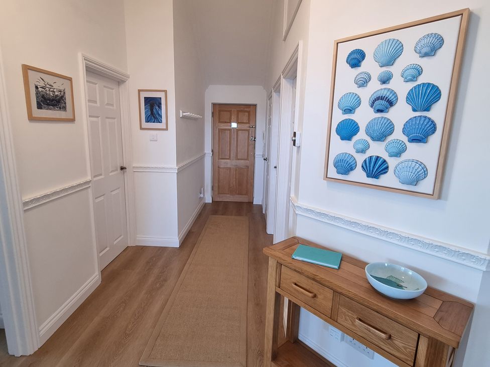 A hallway with artwork, a table, and a rug at 11 Thurlestone Rock in Thurlestone