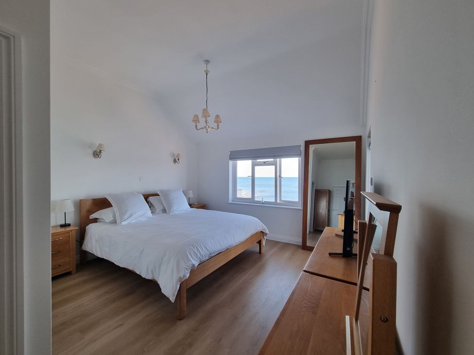 A bedroom with a bed, mirror and window at 11 Thurlestone Rock in Thurlestone