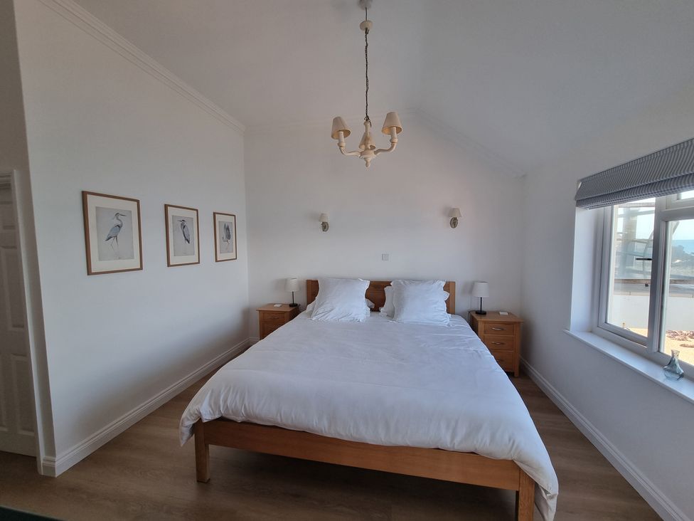A bedroom with a bed and nightstands at 11 Thurlestone Rock in Thurlestone