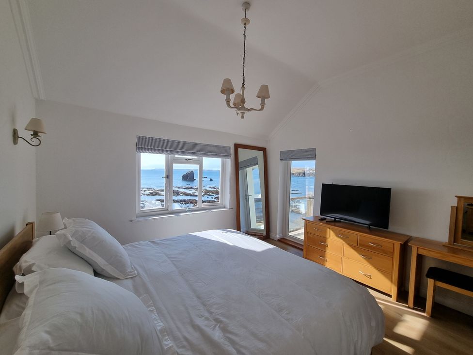 A bedroom with a bed and television at 11 Thurlestone Rock in Thurlestone