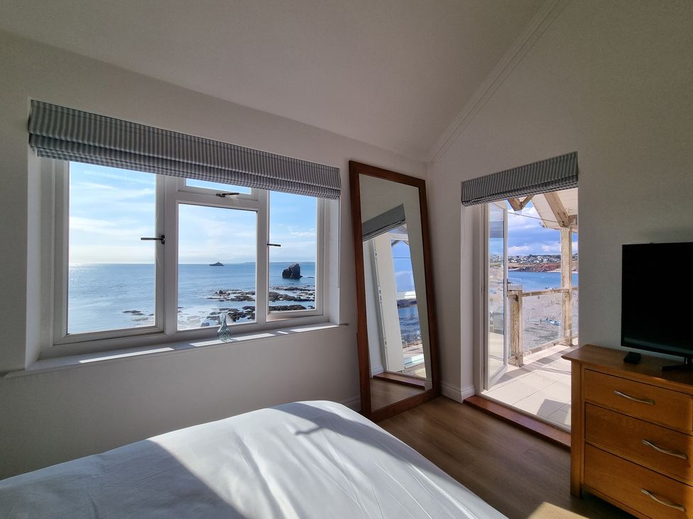 A bedroom with windows and a mirror at 11 Thurlestone Rock in Thurlestone