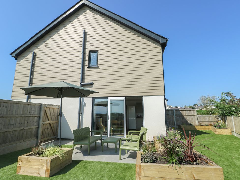 A garden with patio furniture and umbrella at 36 Parc Delfryn