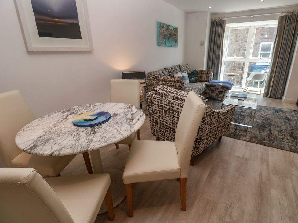 A living room with a table and chairs, a sofa, and artwork at The Trick in Carbis Bay