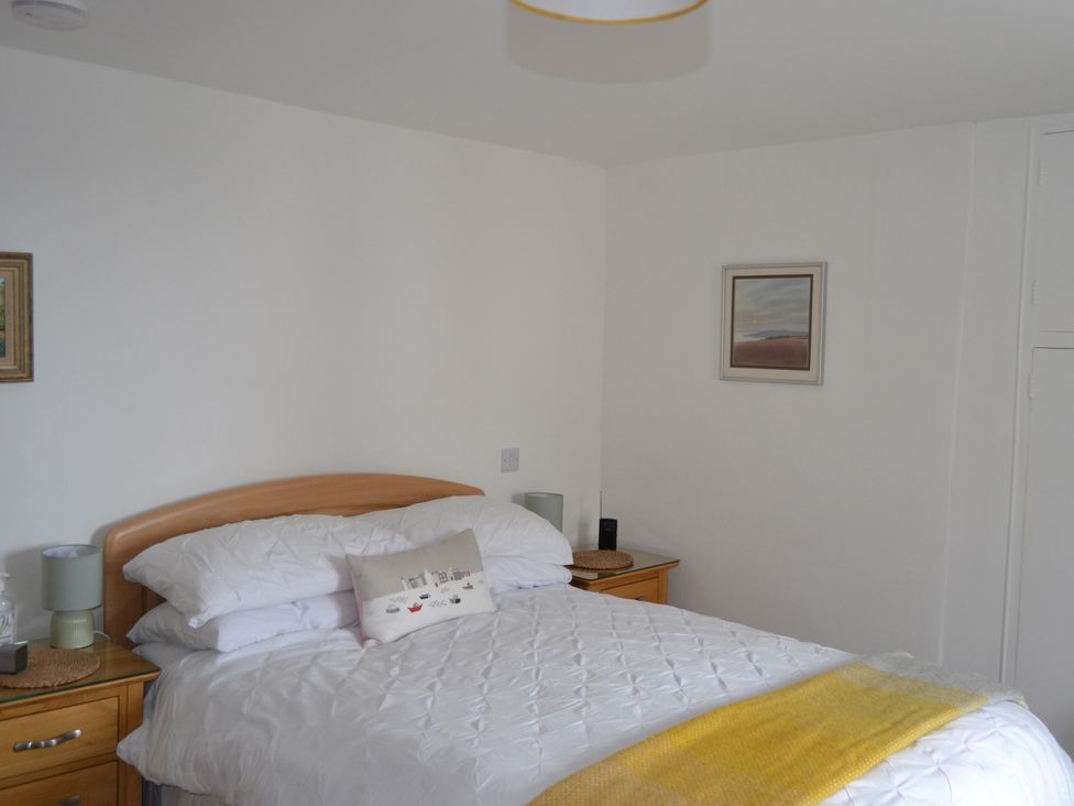 A bedroom with a bed and bedside table at Vine Cottage in East Prawle