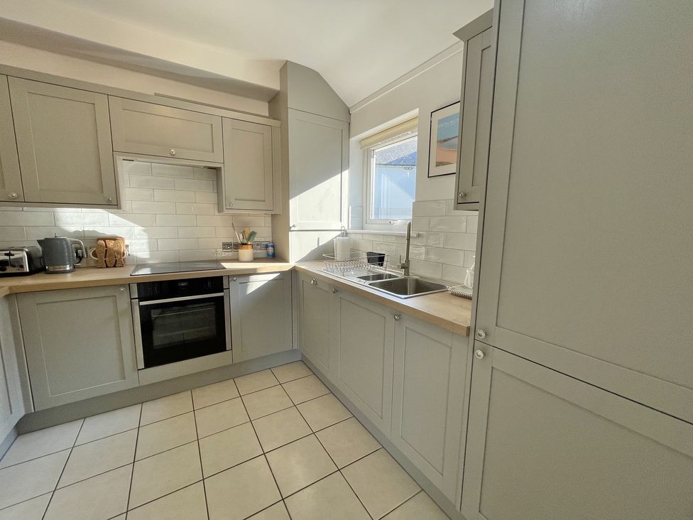 A kitchen with grey cabinets a sink toaster oven and kettle at 12 Thurlestone Rock in Thurlestone