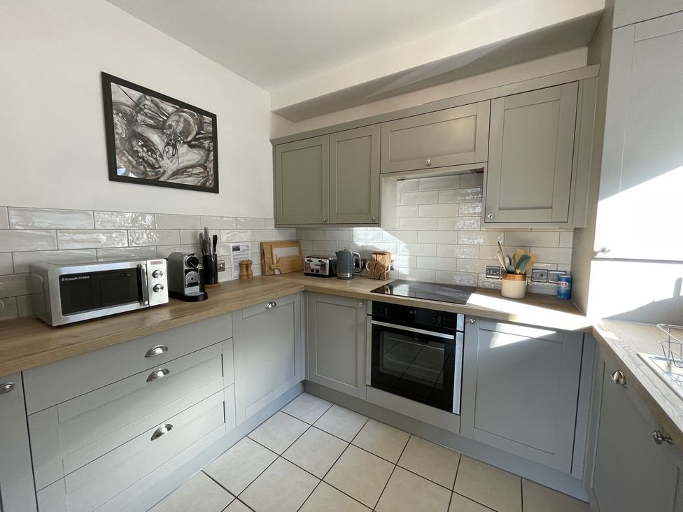 A kitchen with gray cabinets wooden countertops microwave oven toaster kettle and utensils at 12 Thurlestone Rock in Thurlestone