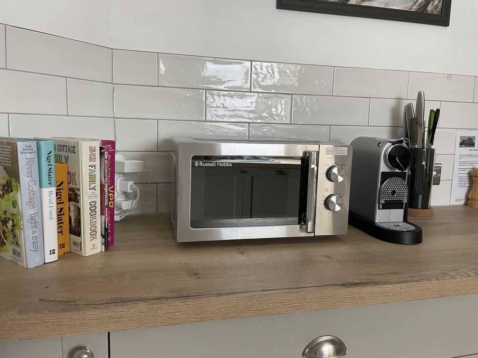 A kitchen counter with cookbooks a microwave a coffee machine and knives in a holder at 12 Thurlestone Rock in Thurlestone