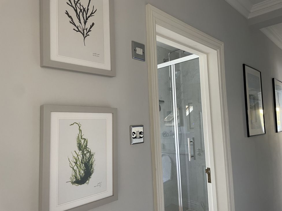 A hallway with framed plant prints on the wall and a glass shower door visible at 12 Thurlestone Rock in Thurlestone