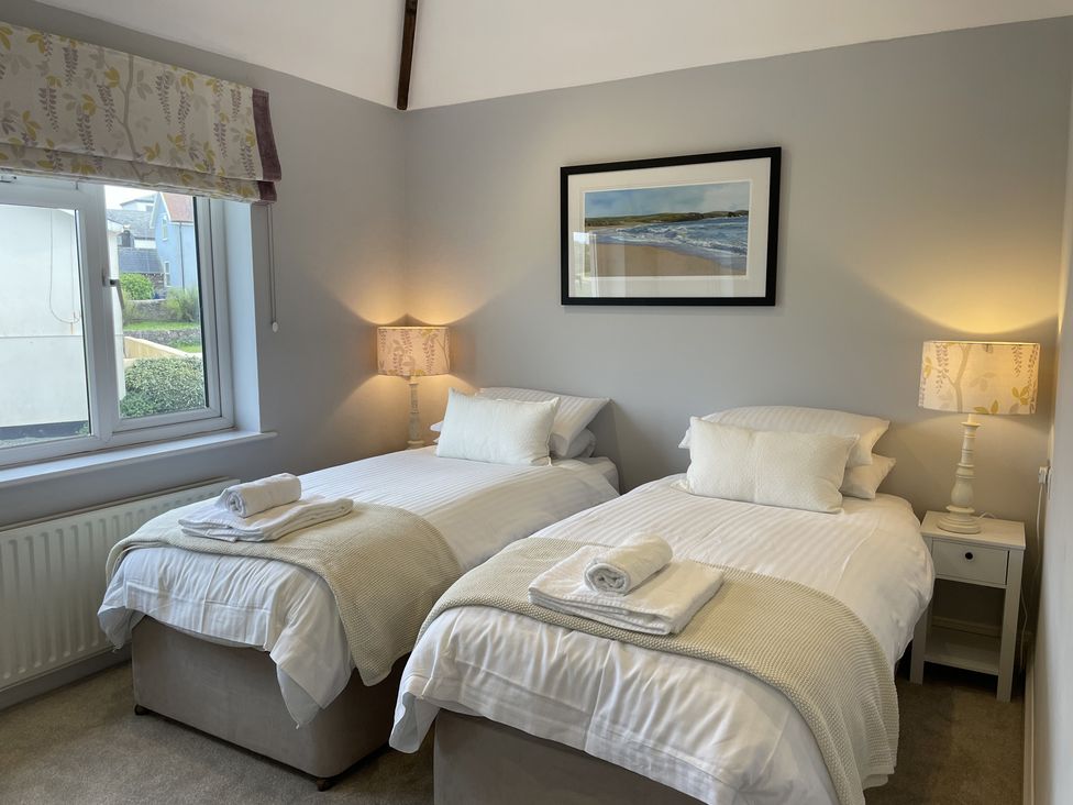 A bedroom with two single beds bedside tables lamps and a framed picture on the wall at 12 Thurlestone Rock in Thurlestone
