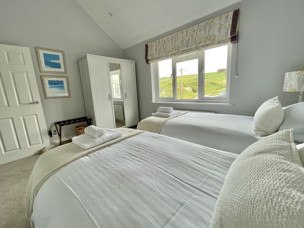 A bedroom with two single beds a white wardrobe and a window showing a green landscape at 12 Thurlestone Rock in Thurlestone