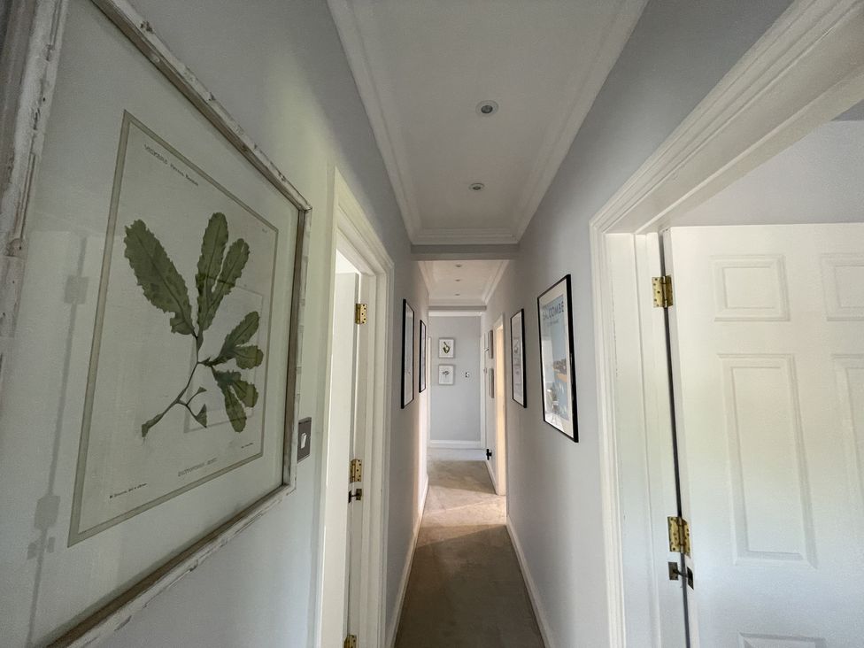 A narrow hallway with framed botanical and landscape prints on the walls at 12 Thurlestone Rock in Thurlestone