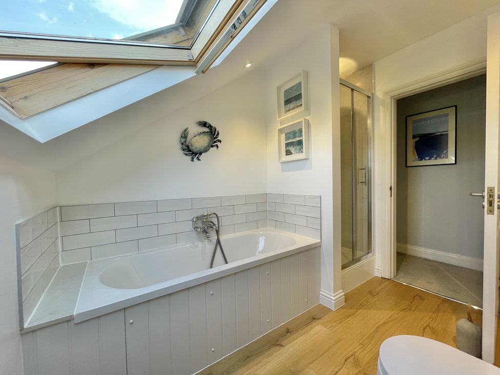 A bathroom with a bathtub and shower cubicle under a skylight at 12 Thurlestone Rock in Thurlestone