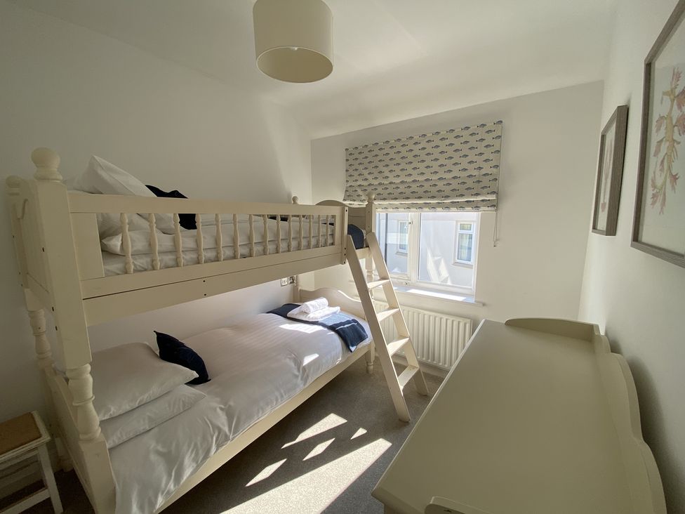 A bedroom with bunk beds beside a window and a chest of drawers at 12 Thurlestone Rock in Thurlestone