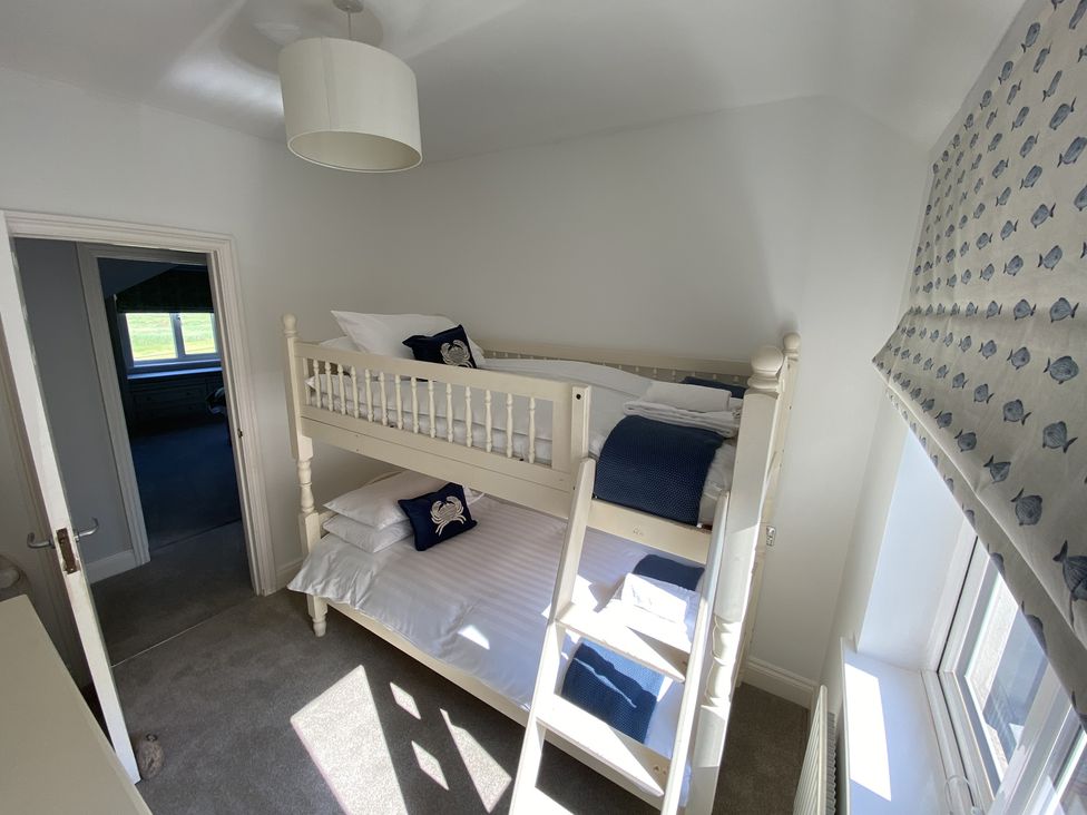 A bedroom with a bunk bed and window with patterned blind at 12 Thurlestone Rock in Thurlestone