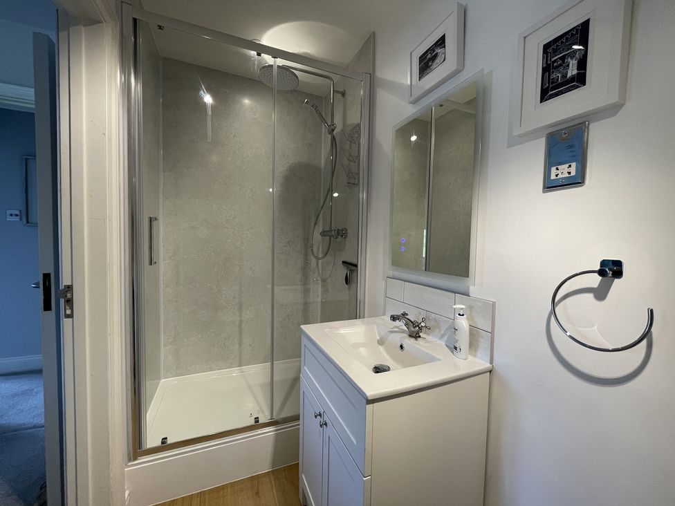 A bathroom with a glass shower enclosure a white vanity with sink and mirror above at 12 Thurlestone Rock in Thurlestone