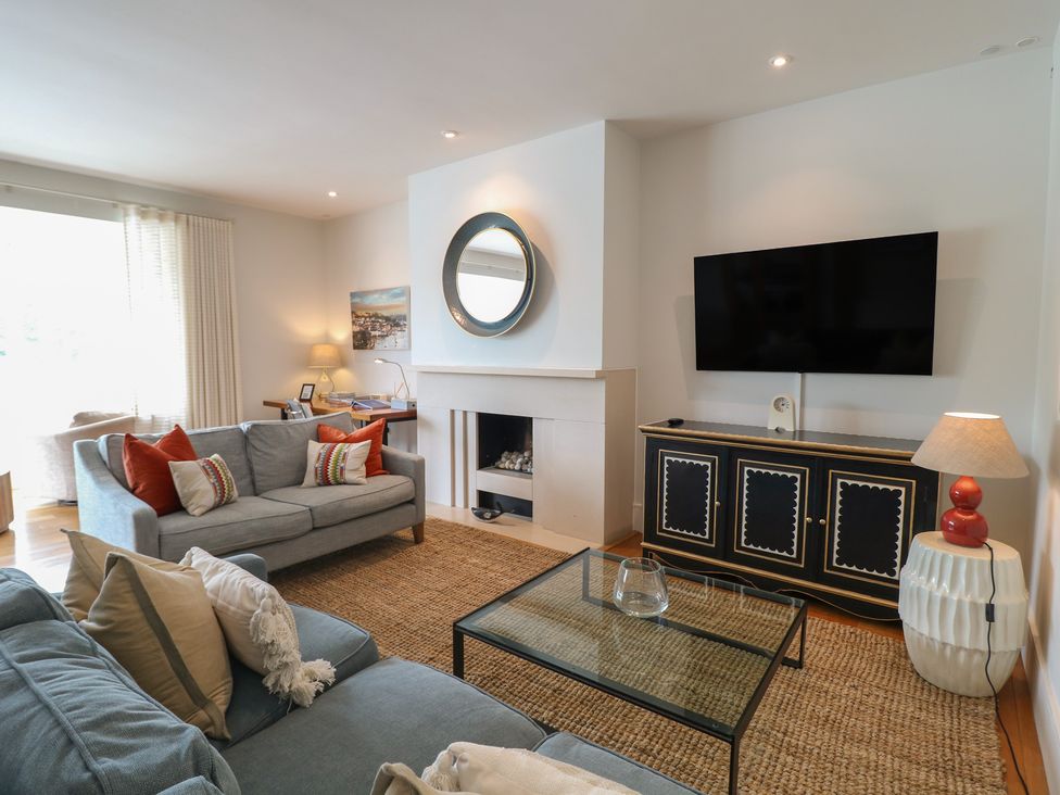 A living room with a sofa, armchair, coffee table, and television at 22 Dart Marina in Dartmouth