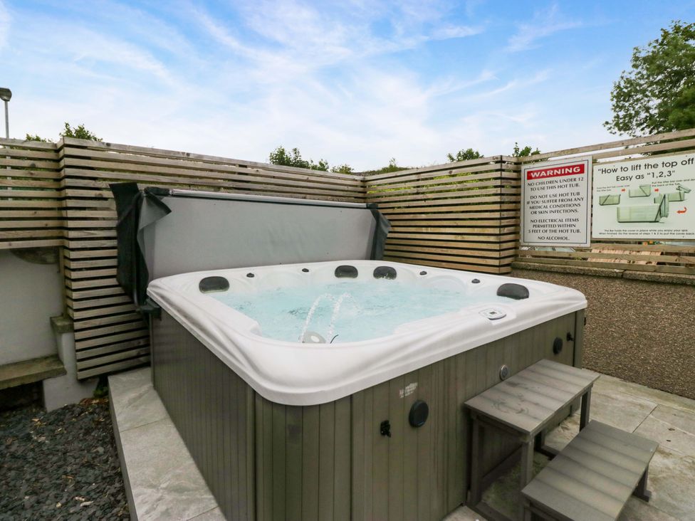 A hot tub with a cover and warning sign in an outdoor area at Lund House Ulverston