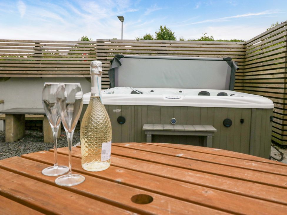 An outdoor area with a hot tub and a table with champagne at Lund House in Ulverston