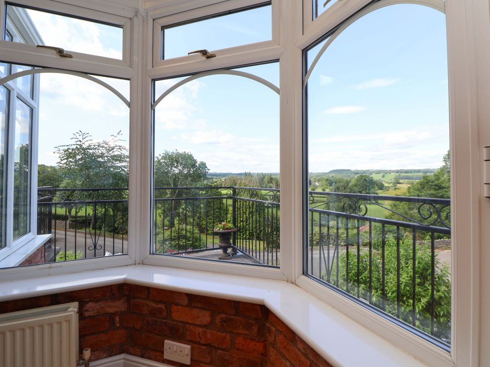 A conservatory with windows and a balcony view at The Old Barn in Pentre Celyn