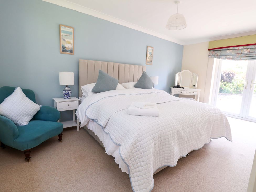 A bedroom with a bed and armchair at The Old Barn in Pentre Celyn