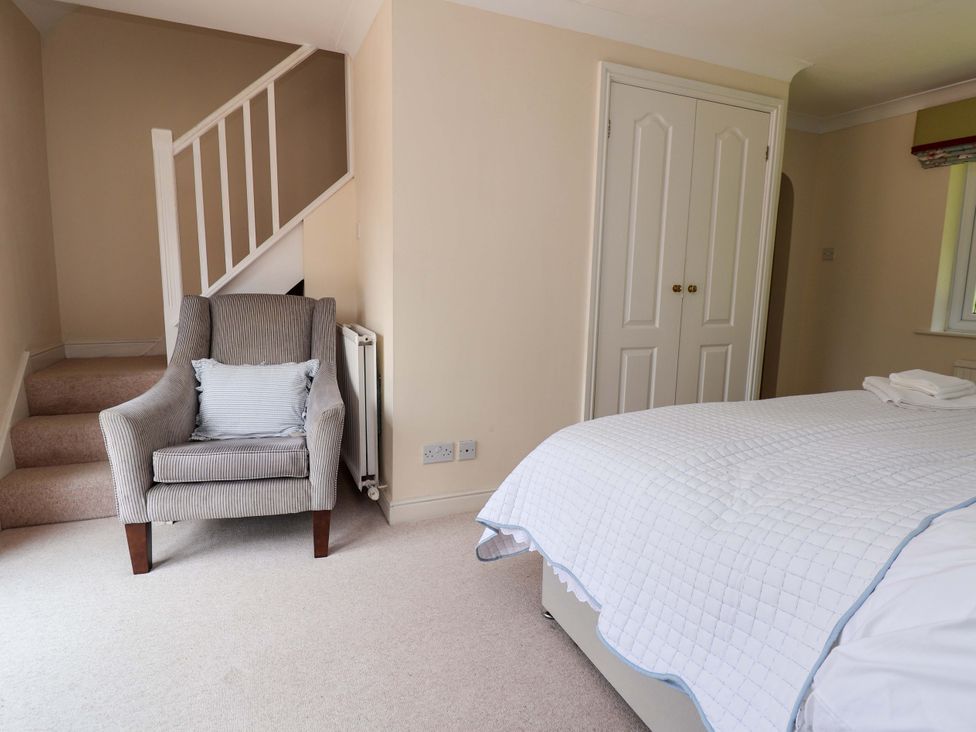 A bedroom with a bed and armchair at The Old Barn in Pentre Celyn
