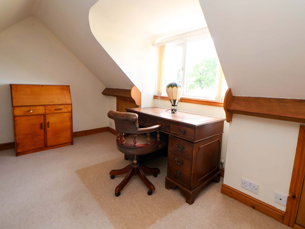 A study with a wooden desk and chair at The Old Barn in Pentre Celyn