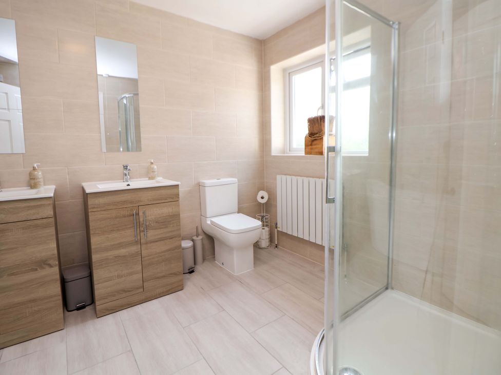 A bathroom with a sink, toilet, and shower at The Old Barn in Pentre Celyn