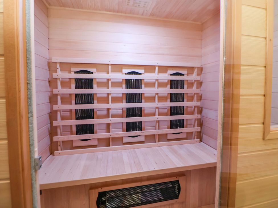 A sauna with wooden paneling and heating elements at The Old Barn in Pentre Celyn