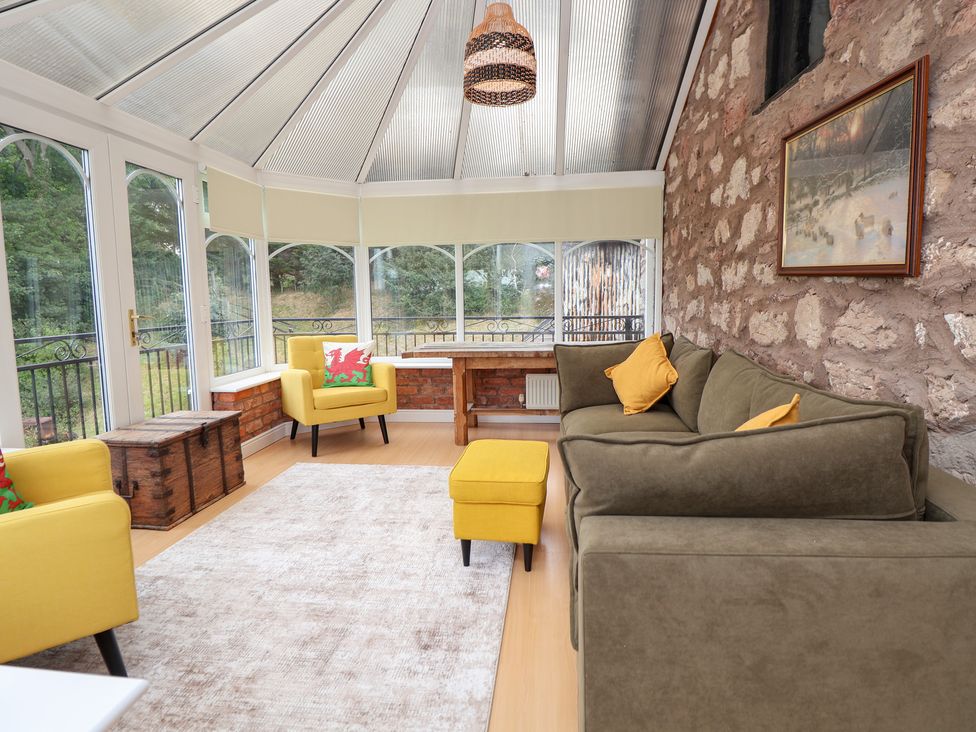 A conservatory with seating and a table at The Old Barn in Pentre Celyn