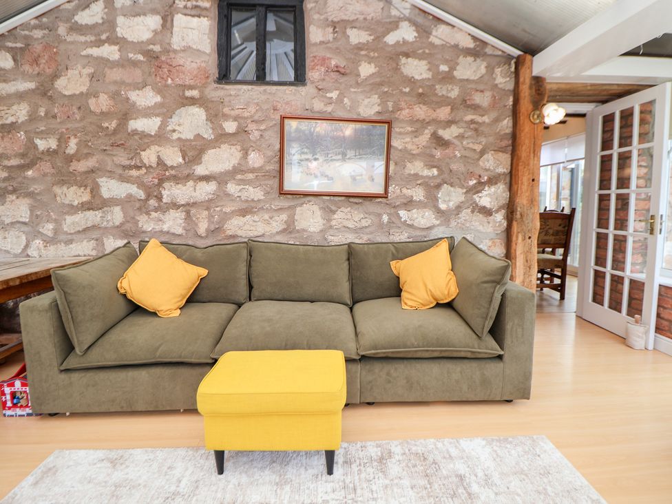 A living room with a sofa and ottoman at The Old Barn in Pentre Celyn