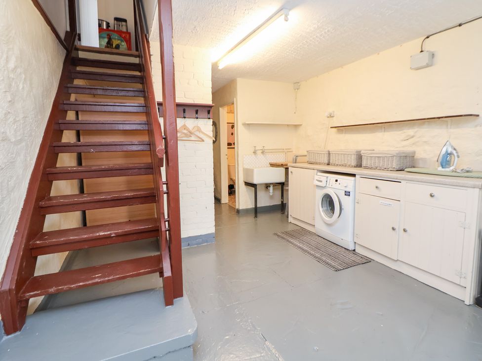 A laundry room with a washing machine and a staircase at The Old Barn in Pentre Celyn