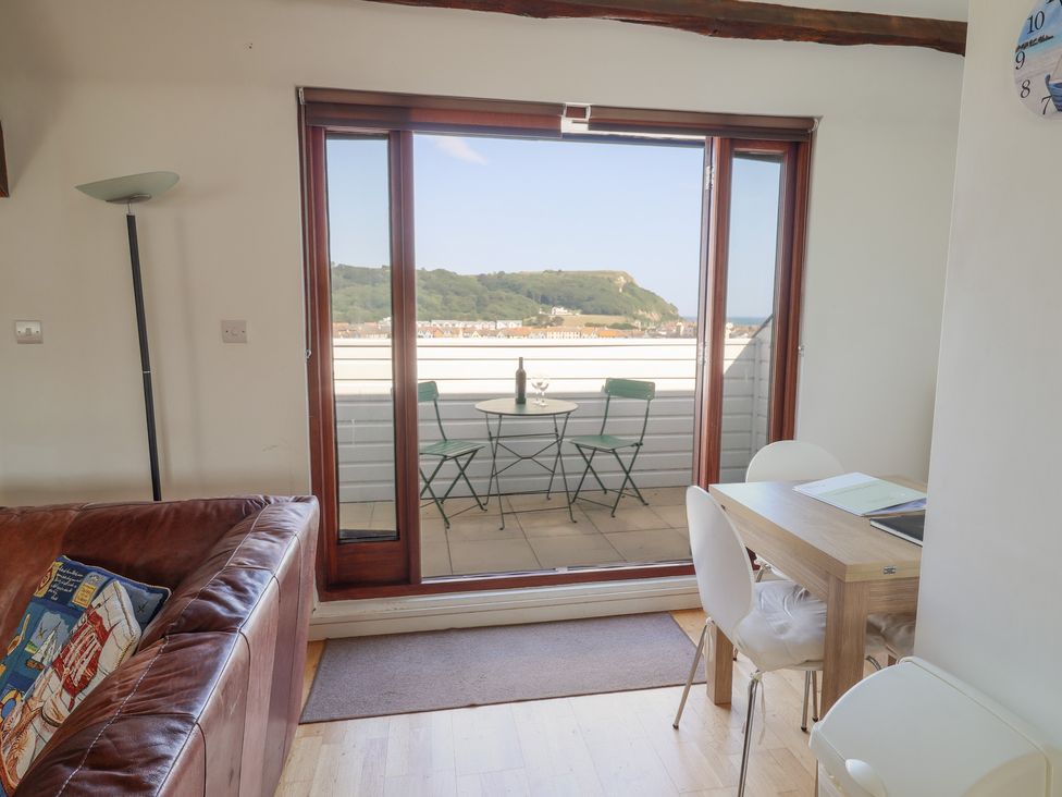 A living room with a table and chairs overlooking a balcony at Cliff View in Seaton