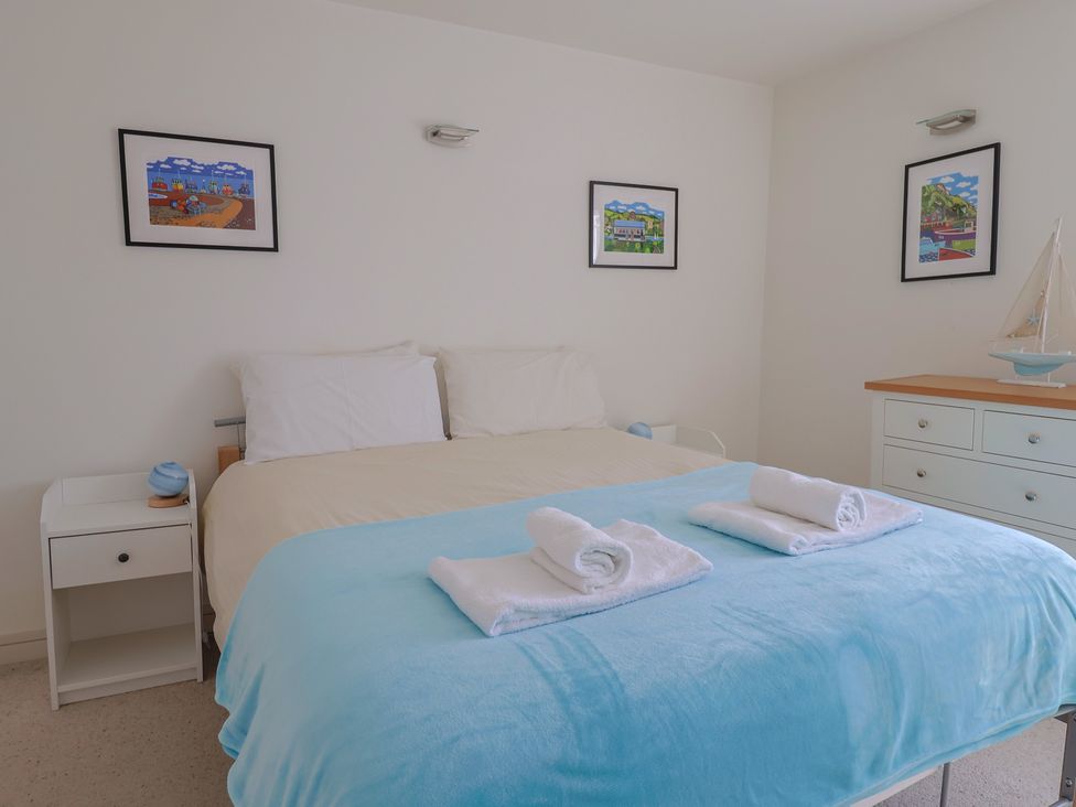 A bedroom with a bed, nightstand, and decorative items at Cliff View in Seaton