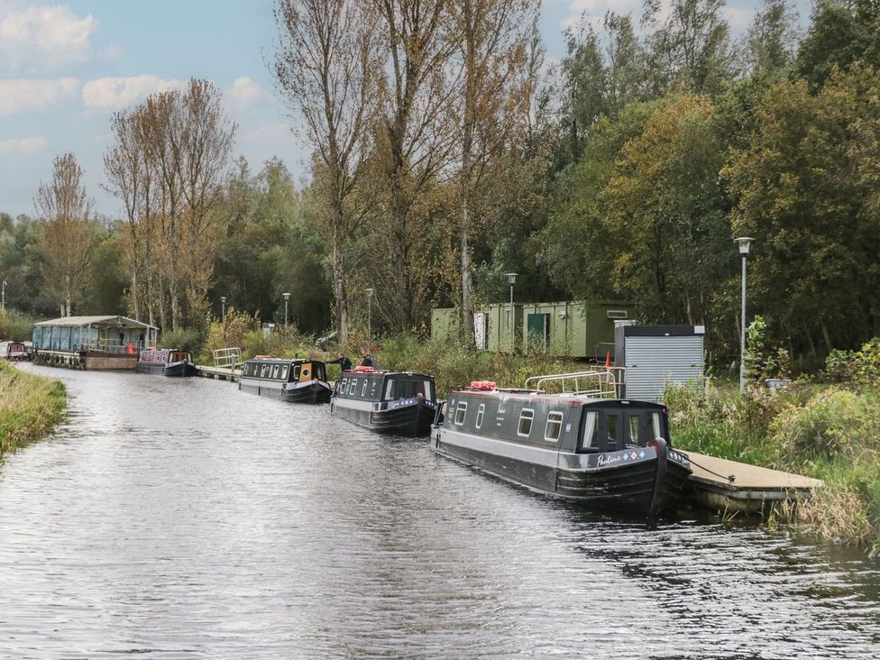 A canal with narrowboats and trees at Yew in Denny