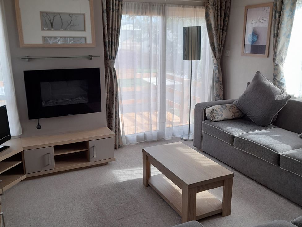 A living room with a coffee table and television at Yew in Denny