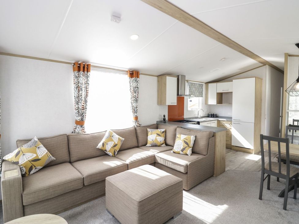A living room with a kitchen and seating area at Ash in Denny