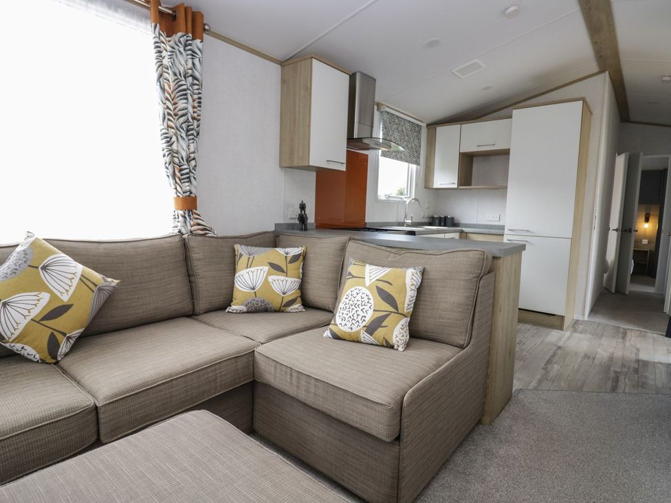 A living room with a sofa and kitchen area at Ash in Denny