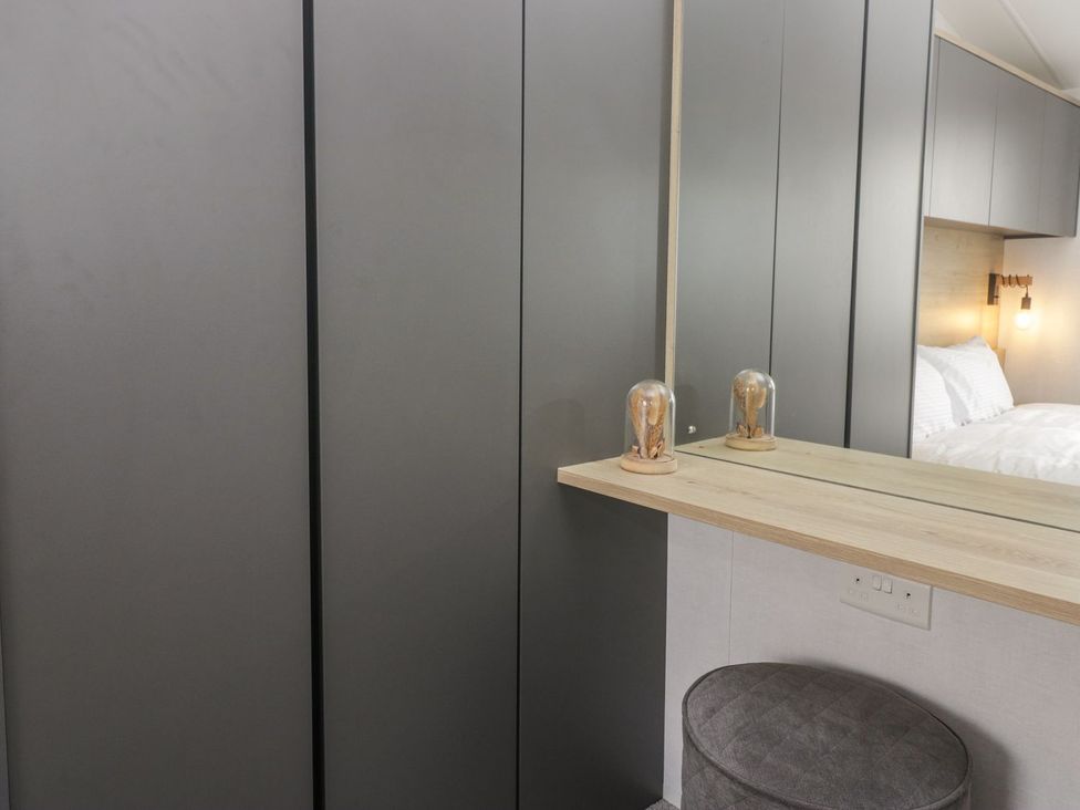 A bedroom with a wardrobe and a mirror at Ash in Denny