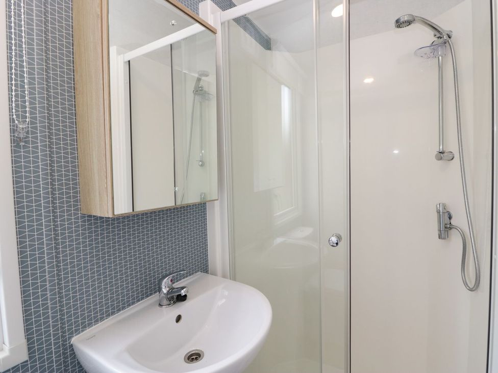A bathroom featuring a shower, mirror, and sink at Ash in Denny