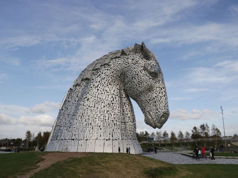 A large horse sculpture with people walking near it at The Kelpies in Falkirk
