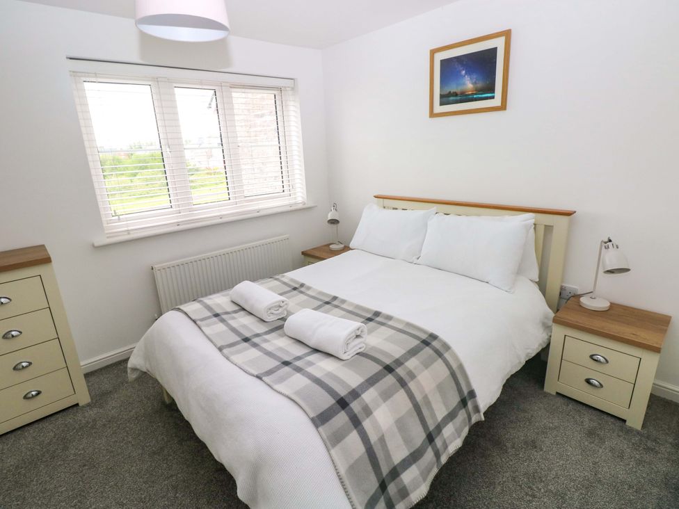 A bedroom with a bed and nightstands at 69 Ffordd Y Meillion in Llanelli