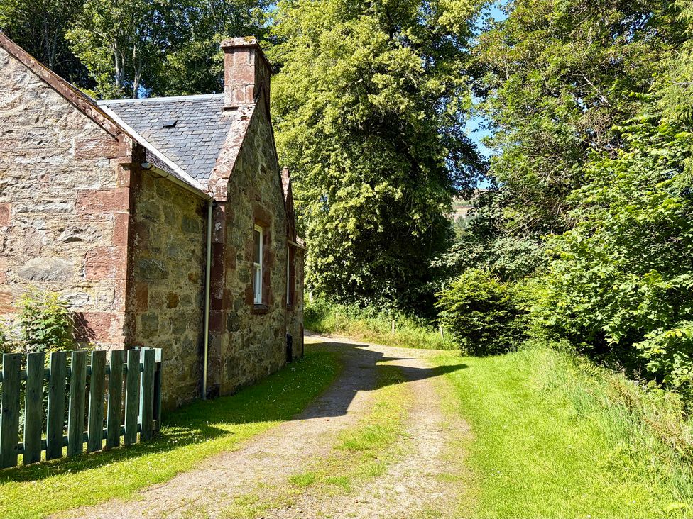 A house next to a path with trees at Gunroom Cottage near Castle Leod