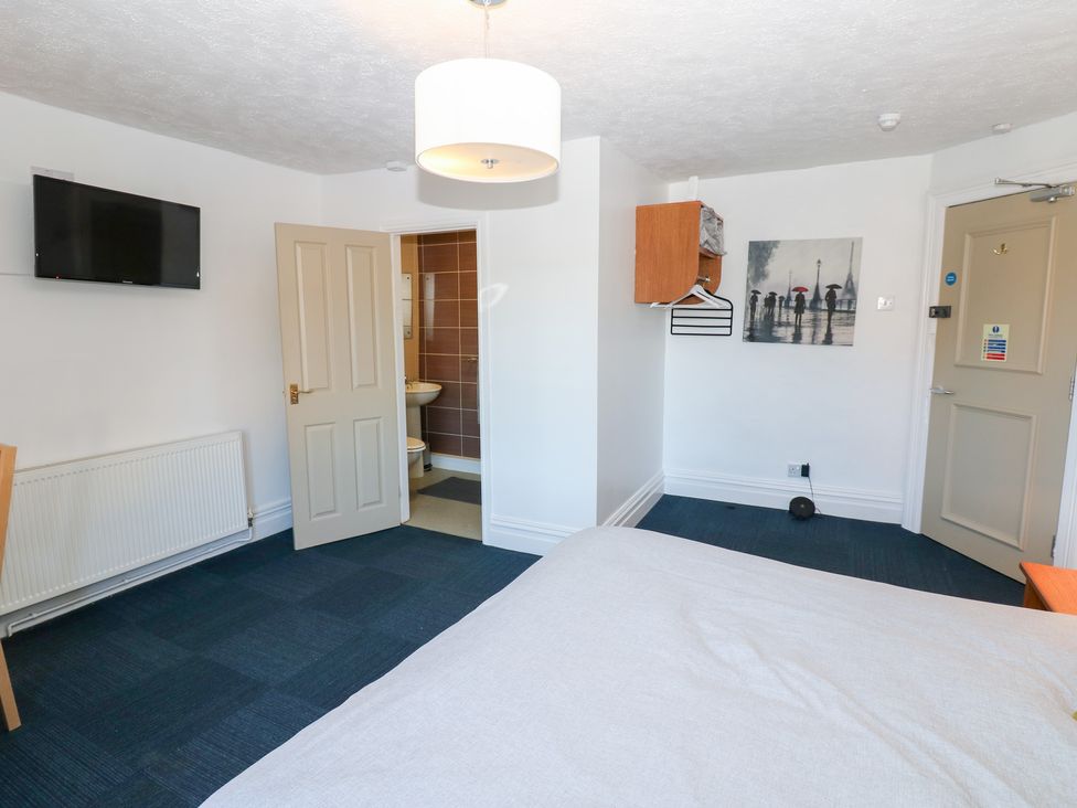 A bedroom with a bed, television, and bathroom door at Bedroom 3 in Bishop Auckland