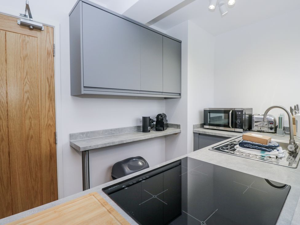 A kitchen with cabinets, microwave, coffee machine, and stovetop at Claife Flights Bowness-On-Windermere