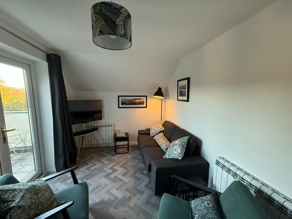 A living room with a television and a sofa at Claife Flights in Bowness-On-Windermere