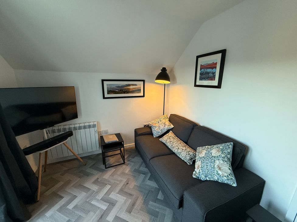 A living room with a television and sofa at Claife Flights in Bowness-On-Windermere