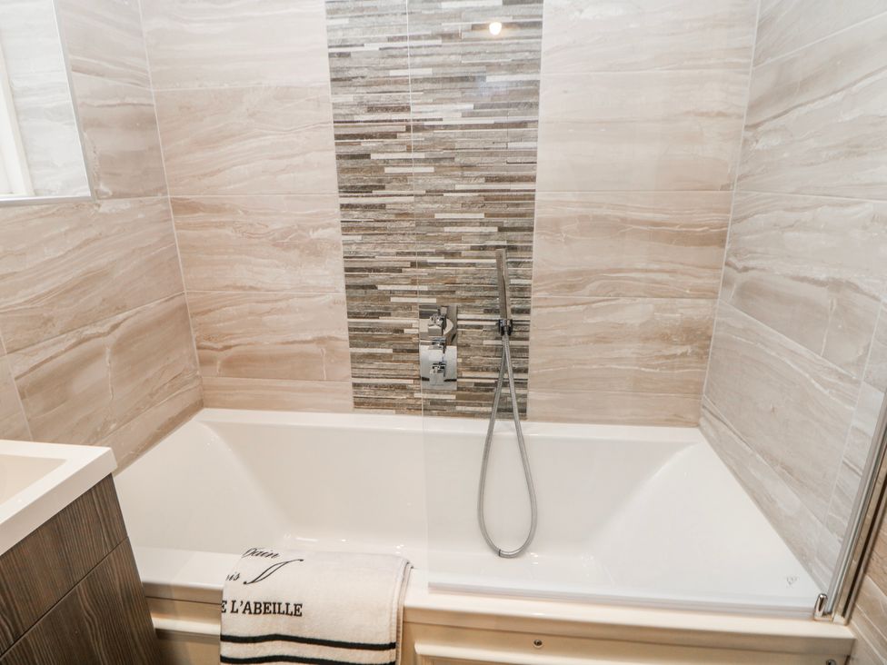 A bathroom with a bathtub and tiled wall at High Tor (84) Studio in Matlock