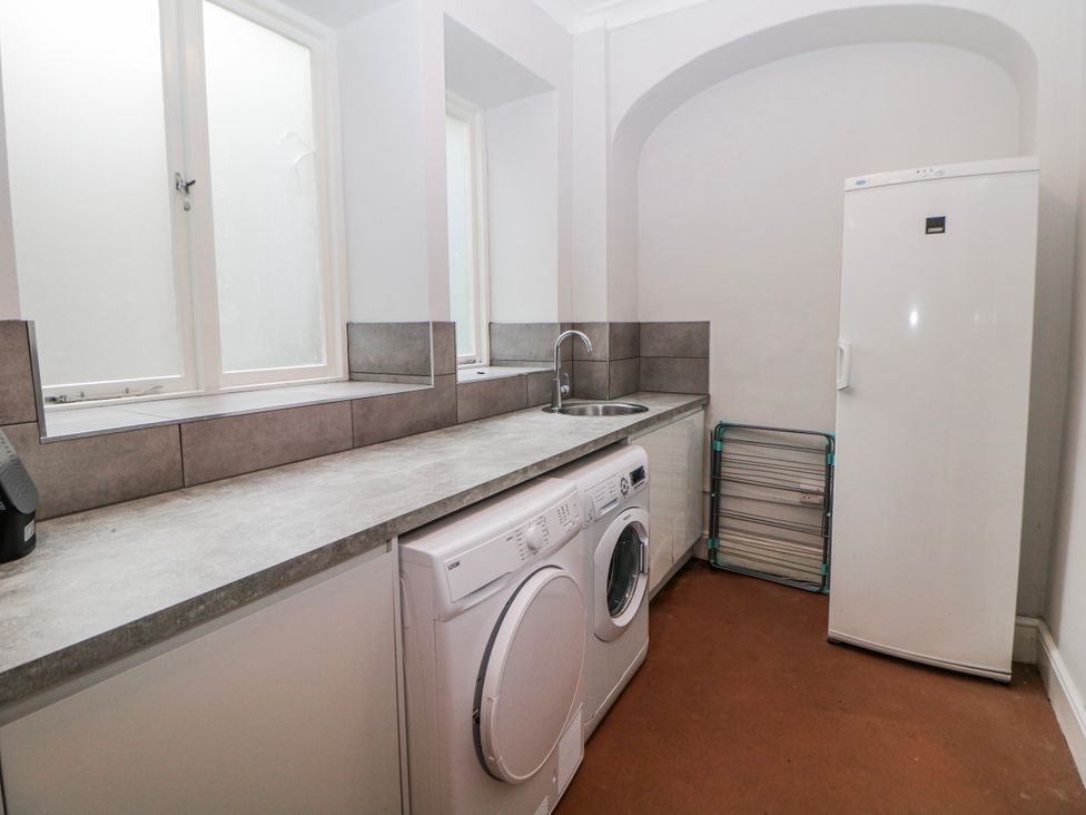 A laundry room with a washing machine and fridge at High Tor (84) Studio Matlock